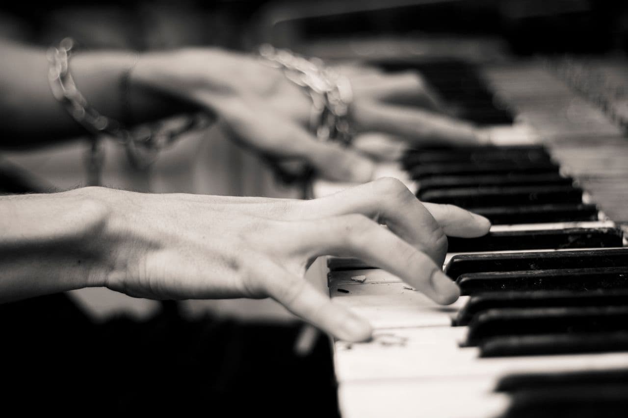Mãos tocando piano em preto e branco